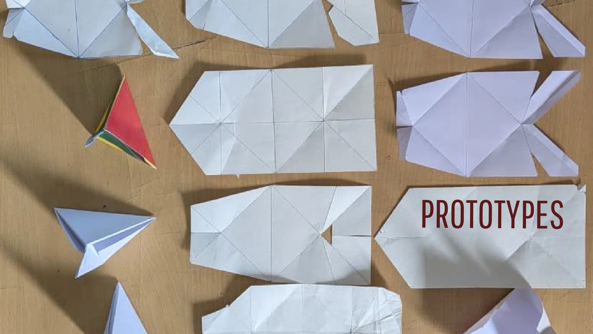 Folded white paper prototypes of the pyramid pack laid out on a table